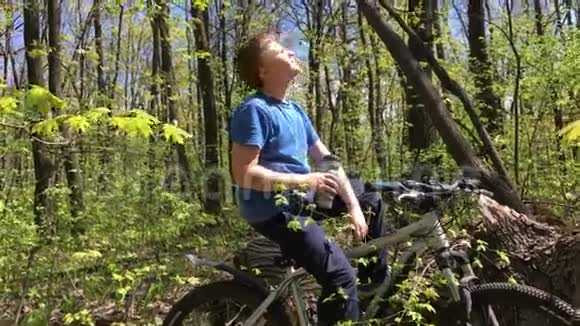 一个骑自行车在树林里喝水的男孩视频的预览图