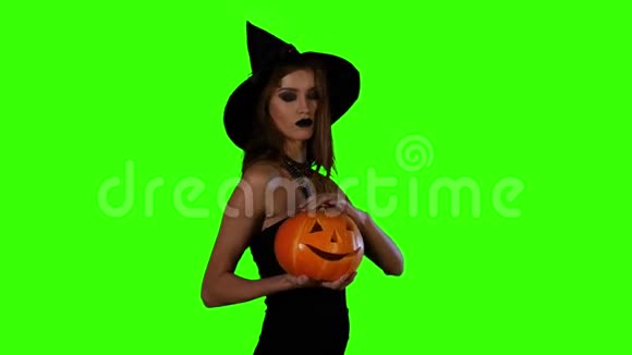 万圣节女巫拿着橙色南瓜在绿色上视频的预览图