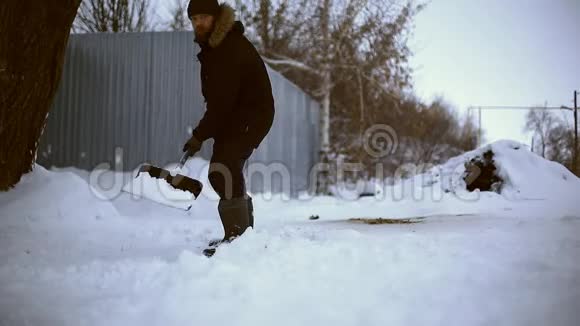 雪夜后工作在一个寒冷的雪天早晨一个拿着铲子把雪从他的院子里移走的人视频的预览图