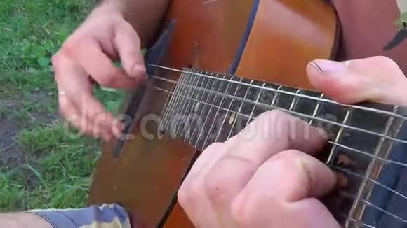 男人优雅地拨弦在自然背景下演奏吉他视频的预览图