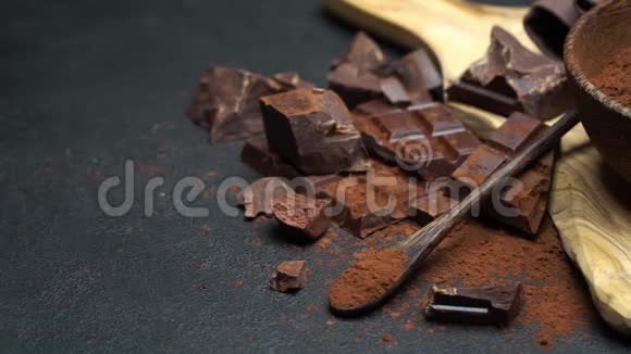 深色巧克力块和可可粉放在深色混凝土背景下的木碗里视频的预览图
