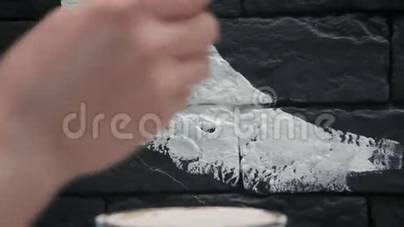 后景年轻的女画家在咖啡店的黑砖墙上做白色图案视频的预览图
