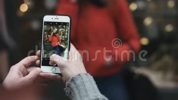 一个男人在户外为他迷人的女孩拍照的特写镜头他用手机拍照视频的预览图