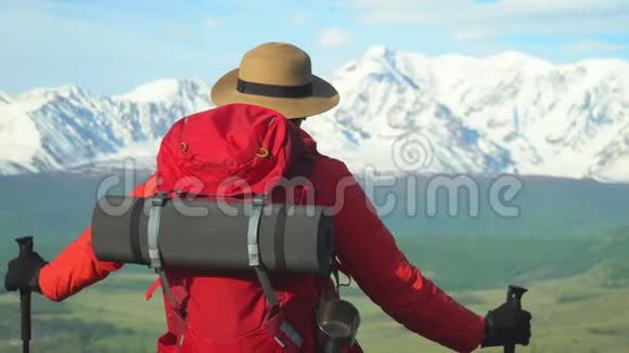 旅行者的女人在岩石上花费看着雪山视频的预览图