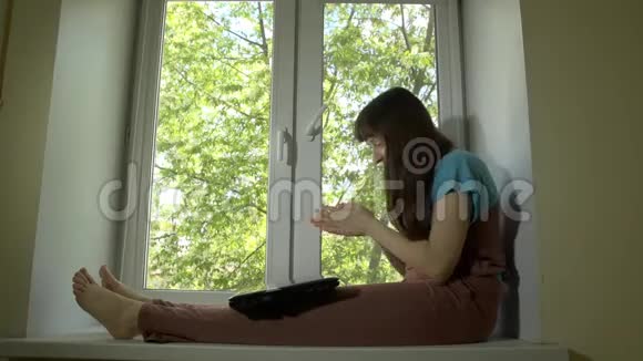 那个女人在窗台上的笔记本电脑后面工作和交流视频的预览图
