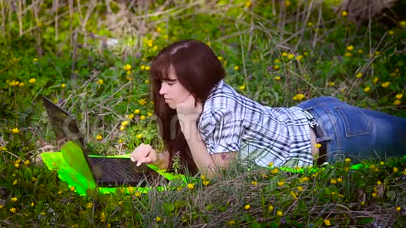 女人躺在草地上的笔记本电脑前休息视频的预览图