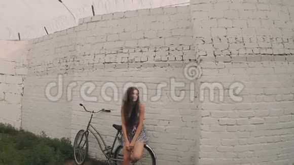 微笑害羞的女孩靠近白墙复古的颜色拍摄年轻女子在靠柱的斜壁附近摆姿势复色视频的预览图