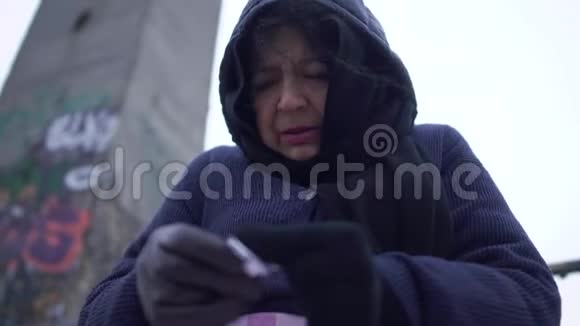 在寒冷多风灰色的天气里老乞丐在桥上请求施舍和帮助视频的预览图