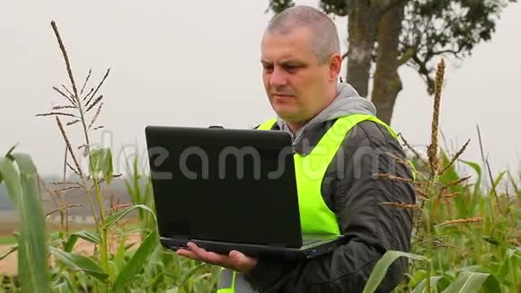 农民用电脑检查田间的玉米视频的预览图