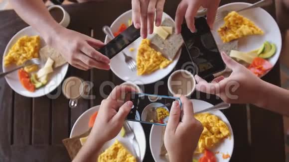 一群朋友在木桌的咖啡馆里吃早餐拍摄煎蛋卷烤面包和咖啡的全景视频的预览图