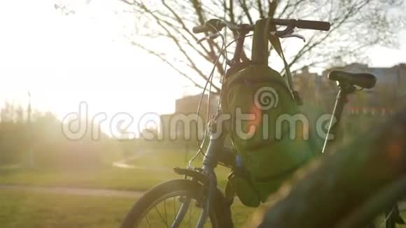 折叠自行车站在公园日落时上面挂着绿色背包视频的预览图