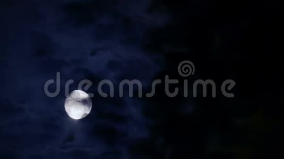 在黑色夜晚移动的云后的满月视频的预览图