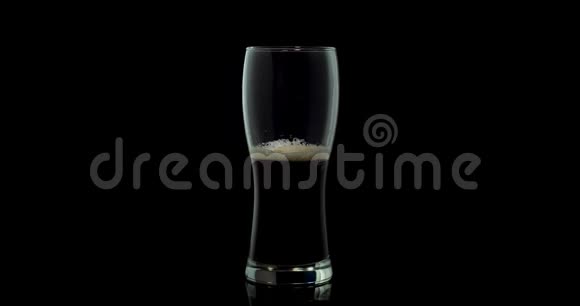 带泡沫的啤酒被倒入一个玻璃中在黑暗的背景下4k视频的预览图