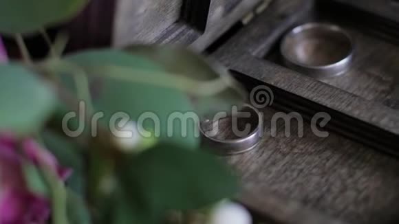 结婚戒指躺在木箱里戒指背景上的婚礼花束慢动作视频的预览图