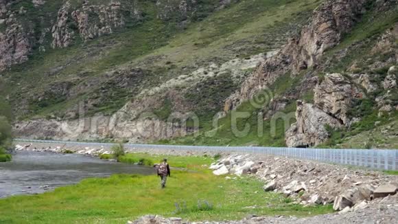 旅行者穿过山脉和河流之间的山谷3840x2160视频的预览图