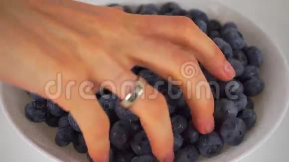 女性用手从4K白色盘子中舀取蓝莓视频的预览图