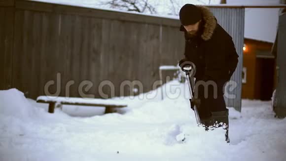 雪夜后工作在一个寒冷的雪天早晨一个拿着铲子把雪从他的院子里移走的人视频的预览图