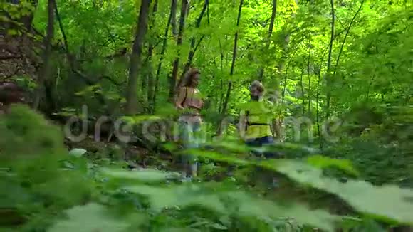 女孩和男人在阳光明媚的夏天森林里徒步旅行4K跟踪Stealam镜头视频的预览图