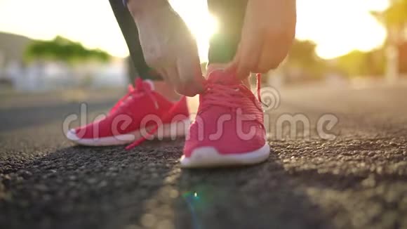 在日落时分女人系鞋带沿着棕榈大道奔跑视频的预览图