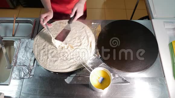 女厨师在炒菜时在厨房里用专业的烤炉做煎饼锅上煎煎饼的过程视频的预览图