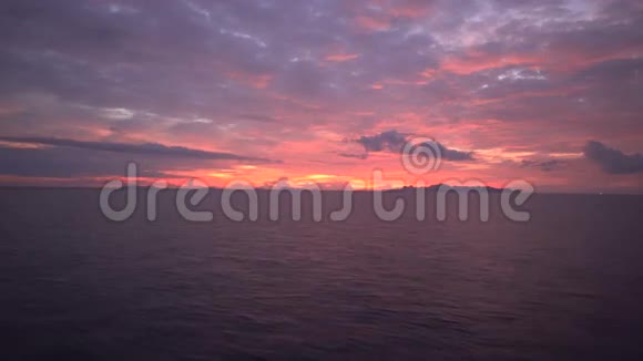 从船上的舷窗俯瞰美丽的日落在波涛汹涌的海面上从移动的船上的甲板上俯瞰大海视频的预览图