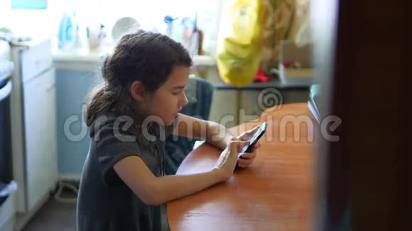女孩早餐在厨房社交媒体玩智能手机网络游戏坐在桌子旁视频的预览图
