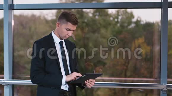 年轻的商人在办公室橱窗里用平板电脑视频的预览图