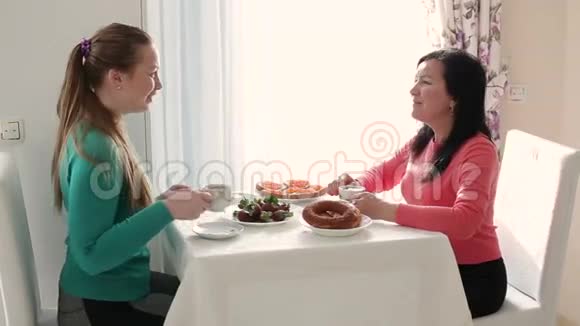 两个年轻女人在喝咖啡早餐两个年轻女人年轻的女人喝咖啡说话一次谈话视频的预览图