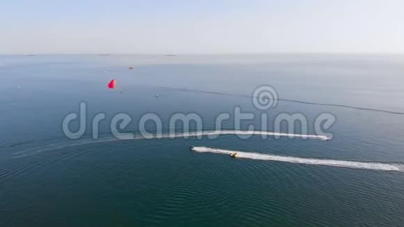 在日落时分用红色降落伞拖着一个jetski在海边的海面上视频的预览图