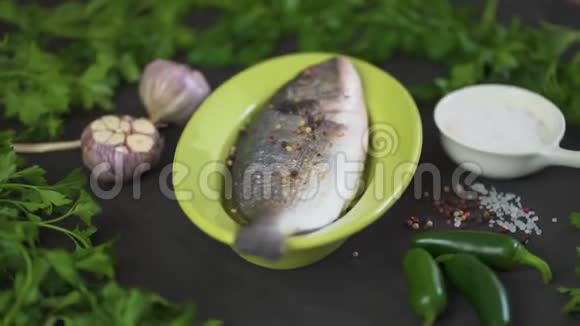 新鲜的生的多拉达鱼放在绿色的盘子里黑桌上放着一套蔬菜视频的预览图