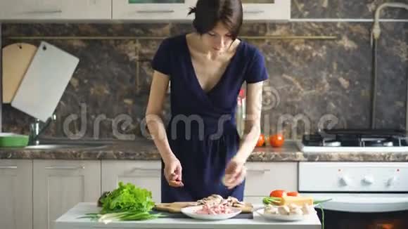 年轻漂亮的女人在家里的厨房里用木板切蘑菇做披萨视频的预览图