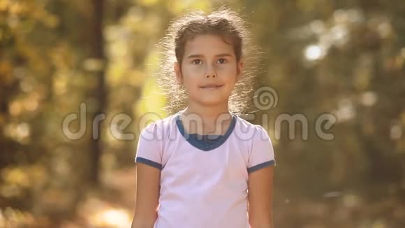 黄秋林中的小姑娘美丽的阳光小女孩走在秋天的森林自然生活方式视频的预览图