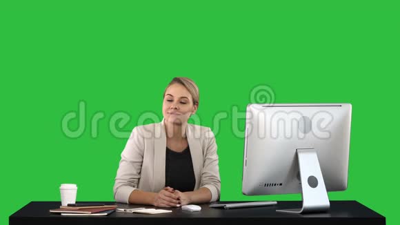 年轻女子美女看着并微笑着在绿色屏幕上拍摄色度键视频的预览图
