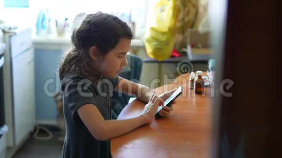 在厨房玩智能手机的少女上网游戏视频的预览图
