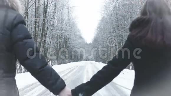 女孩和男孩沿着马路走进树林握住手视频的预览图