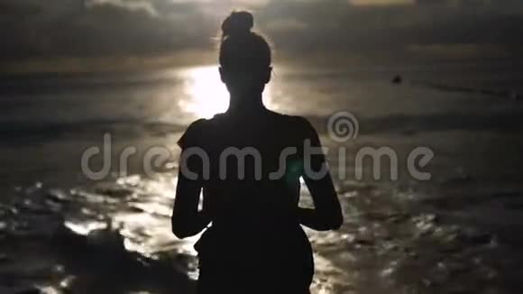 女人的轮廓越过夕阳的天空黑色的影子的女性身体与手举起来视频的预览图