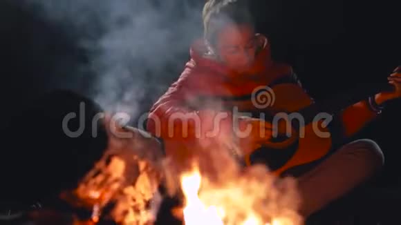 坐在篝火旁的年轻女子视频的预览图