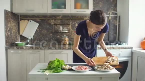 年轻漂亮的女人在家里的厨房里用木板切蘑菇做披萨视频的预览图