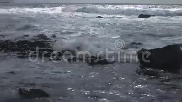 海浪覆盖海滩上的小岩石视频的预览图