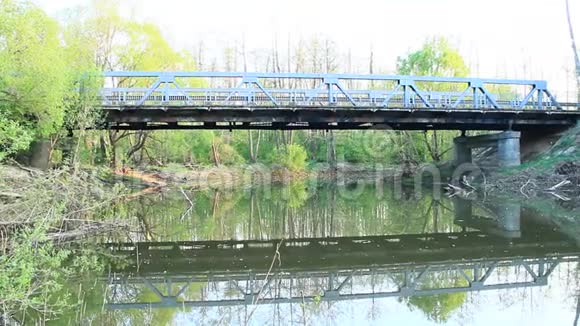 在平静的春日里跨河的汽车桥在水中反射森林池塘视频的预览图