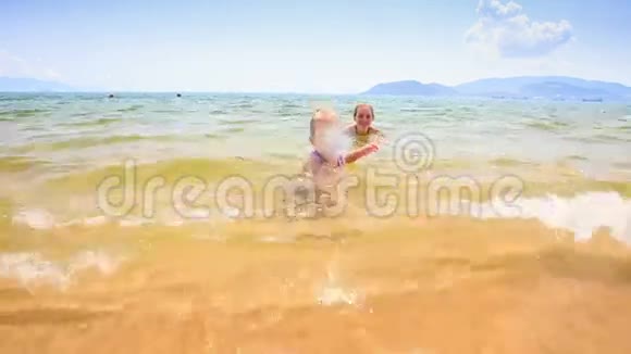 浅海沙滩上的金发小女孩带着球跑视频的预览图