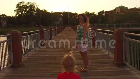 日落时分母亲和女儿在码头上散步视频的预览图