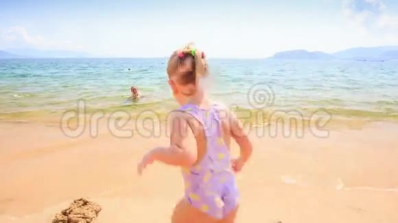 特写金发小女孩从海里跑到沙滩视频的预览图