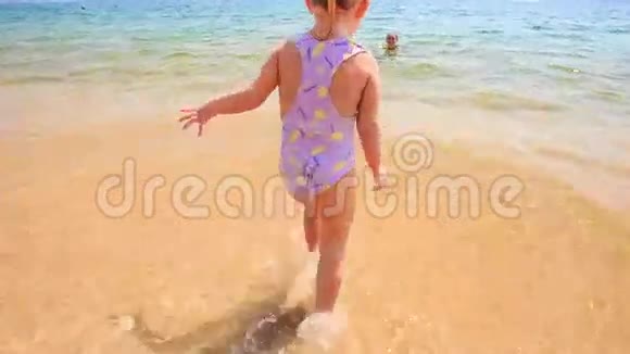 特写金发小女孩从海里跑到沙滩视频的预览图