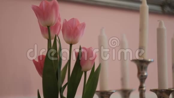 客厅桌子上有粉红色的郁金香和白色的蜡烛视频的预览图