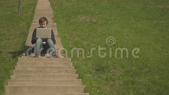 青年男子坐在公园楼梯上的前景视频的预览图