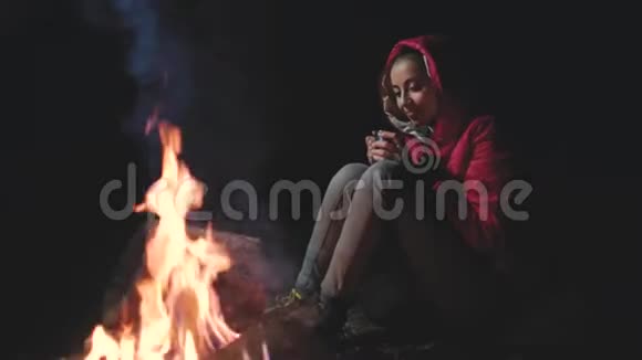 坐在篝火旁的年轻女子视频的预览图