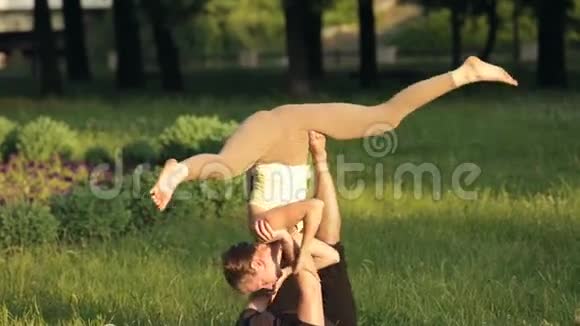 很棒的一对练习杂技瑜伽专业瑜伽教练在城市公园练习两名成功青年视频的预览图