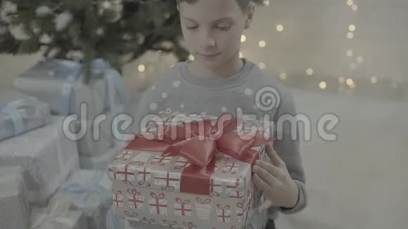 兴奋的小快乐男孩小孩在装饰的新年树节日气氛室内打开圣诞礼物盒视频的预览图