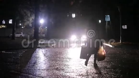 女人带着一个手提箱和一个袋子穿过黑暗的院子视频的预览图